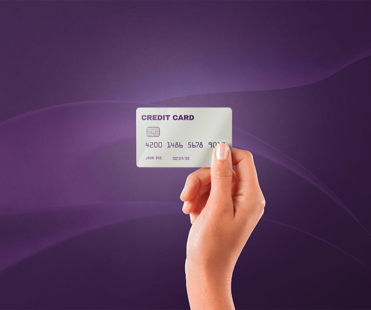 Mano sosteniendo una tarjeta de crédito sobre fondo morado